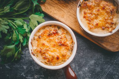 Porsiyonlar halinde Julienne, kremalı ve peynirli mantarlar, karanlık arka planda restoran yemekleri.