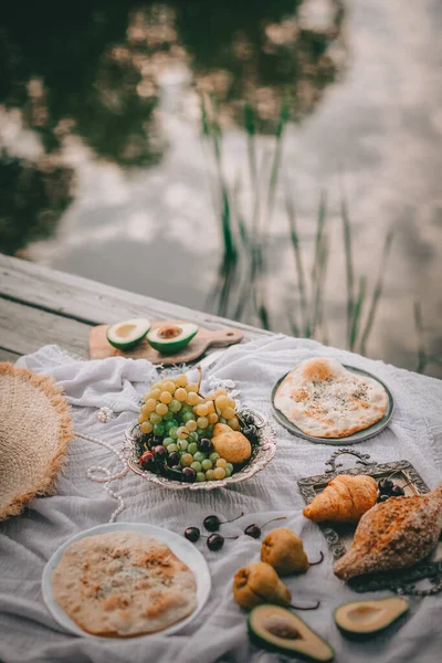 Picnic in vintage style, Fruits and bread with vintage dishes, decorations on a wooden back near water