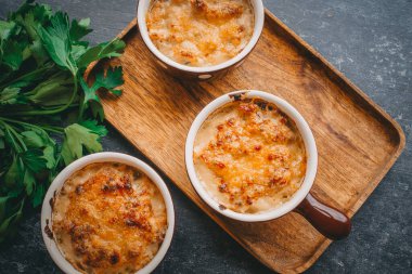 Porsiyonlar halinde Julienne, kremalı ve peynirli mantarlar, karanlık arka planda restoran yemekleri.