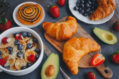 Kahvaltı, böğürtlenli mini krep, kruvasan ve avokado nefis yaz yemekleri, koyu bir sırt manzarası.