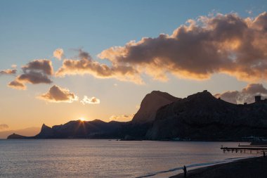 Gün batımında deniz kenarında dağlar