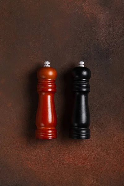 Wooden pepper mill and salt shaker mill on dark background top view