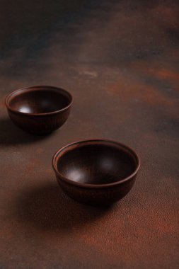 Kahverengi arka planda iki koyu el yapımı kil kase.