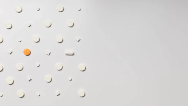 One colored pill on a background of white pills