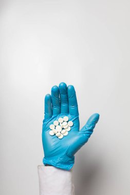 Eldivendeki bir elin içinde bir avuç hap var.