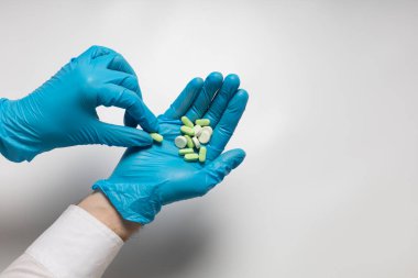 Eldivendeki bir elin içinde bir avuç hap var.