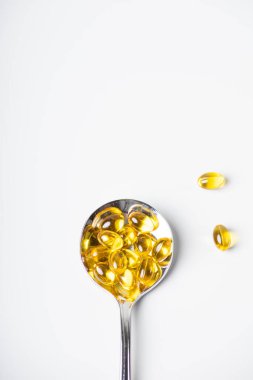 Hafif arka planda bir kaşık omega-3 vitamini.
