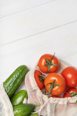 Taze sebzeler, domatesler ve salatalıklar çevre dostu torbalarda.