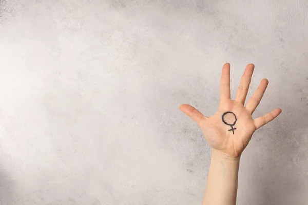 Female hand with female symbol of Venus on grey background for international womens day
