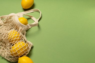 Yeşil arka planda çevre dostu bir çantada limonlar