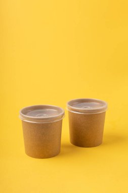 Sarı arka planda tek kullanımlık yiyecek kutuları.