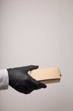 Eldiven içindeki kuryenin elinde bir teslimat kutusu var.