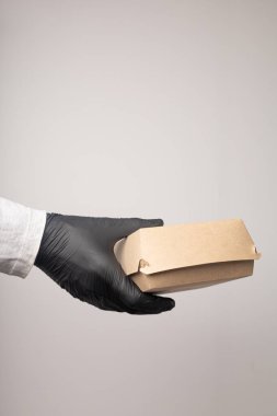 Eldiven içindeki kuryenin elinde bir teslimat kutusu var.