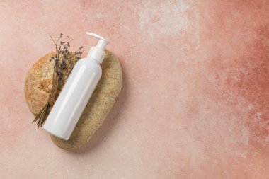 Pembe arka plan ve taşlarda lavanta kremi olan maket şişesi.