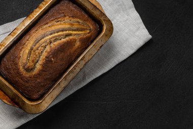 Tekstil peçetesi ve siyah arkaplanda dikdörtgen şeklinde taze muz ekmeği.