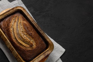 Tekstil peçetesi ve siyah arkaplanda dikdörtgen şeklinde taze muz ekmeği.