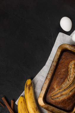 Koyu arkaplanda malzemelerle birlikte taze muz ekmeğini dikdörtgen pişirme kabında hazırlayın.