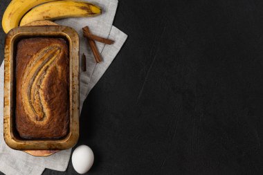 Koyu arkaplanda malzemelerle birlikte taze muz ekmeğini dikdörtgen pişirme kabında hazırlayın.