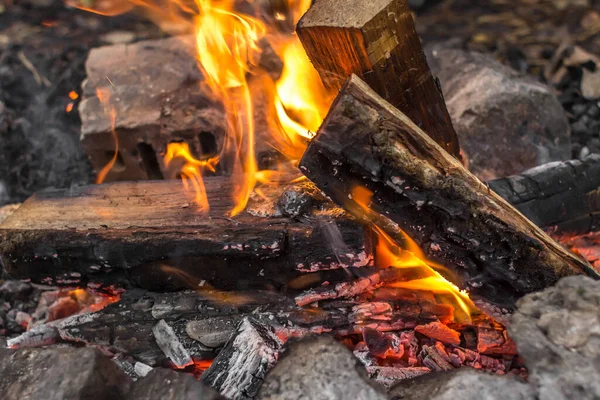 Bright flames. Fire sparks. Burning firewood. Crackling logs on fire. Smouldering coals. Christmas background. The heat and warmth of an open fire. Risk of fire. Dangerous behavior with fire.