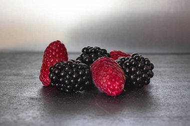 Yaz meyveleri. Olgun ahududu ve böğürtlen. Sağlıklı beslenme. Sağlıklı yiyecekler. Tatlı olarak meyve suyu. Kafe ve restoran için arka plan. Lezzetli sakin hayat. Mevsimlik ürünler. Kırmızı ve siyah.