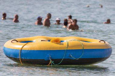 Yuvarlak şişme yatak. Deniz kenarındaki yetişkinler ve çocuklar için eğlence. Aktif dinlenme. Su oyunları. Deniz dalgalarında sörf yap. Suda hız. Büyük şişme daire. Yaz tatili. Güney tatil köyü.