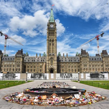 Ottawa, Kanada - 30 Haziran 2021: Parlemento Tepesi 'nde Centennial Flame yakınlarında, kalıntıları eski İkamet Okulları yakınlarında bulunan çocukların anısına bırakılan ayakkabı ve oyuncaklar. Kanada bayrağı yarıya iniyor..