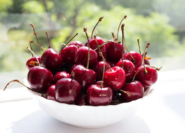 Background with cherry berries in a white plate — Stock Photo, Image