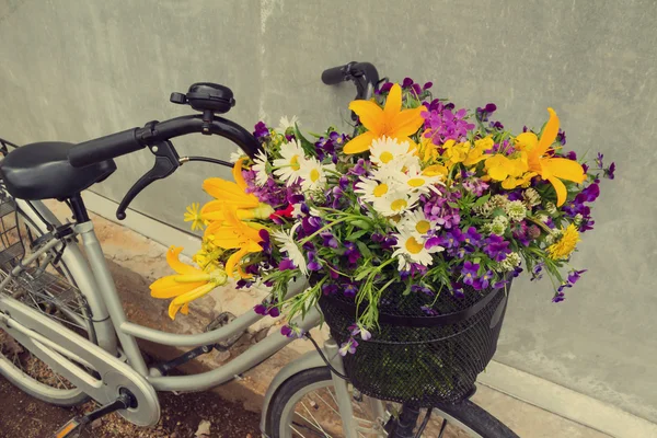 Foto de uma bicicleta com uma cesta cheia de flores de campo — Fotografia de Stock
