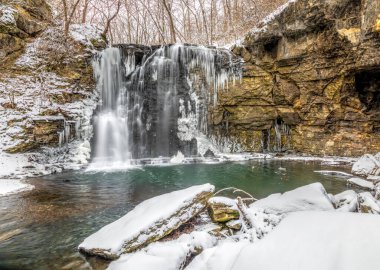 Hayden Run Falls, a secluded waterfall in Columbus, Ohio, is surrounded by winter snow with icicles freezing on rock walls. clipart