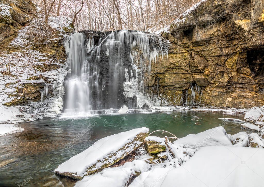 Hayden Run Falls, a secluded waterfall in Columbus, Ohio, is surrounded by winter snow with icicles freezing on rock walls.