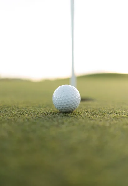 Gold ball close to cup hole on putting green — Stock Photo, Image