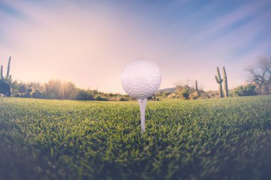 Geniş açı tee ile çöl fairway ve çarpıcı Arizona günbatımı arka planda üzerinde golf topu bakış açısı