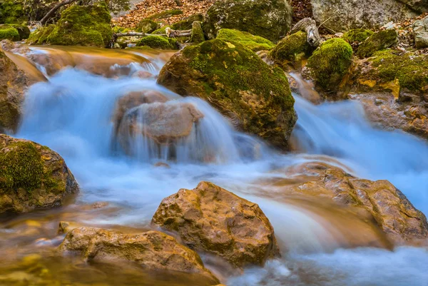 Pequeno rio de montanha que corre sobre umas pedras — Fotografia de Stock