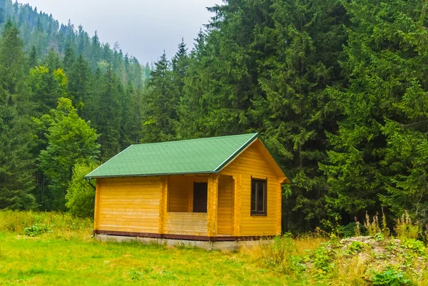 Pequeña casa de madera entre un claro del bosque — Foto de Stock