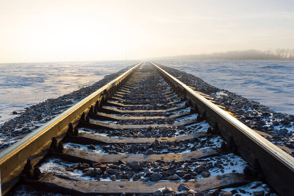 Крупная железная дорога среди заснеженной равнины на восходе солнца