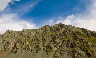 Mavi bulutlu gökyüzü arka planında dağ zinciri, açık hava seyahat sahnesi