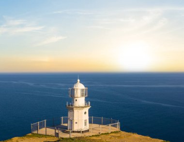 Gün batımında deniz fenerinde beyaz deniz feneri