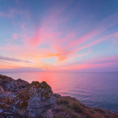 stony sea cliff at the dramatic sunset
