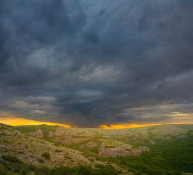 green mountain valley under dense dark cloudy sky, dramatic mountain sunset scene