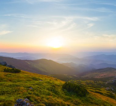 Gündoğumunda yeşil dağ vadisi, dağ arka planında seyahat