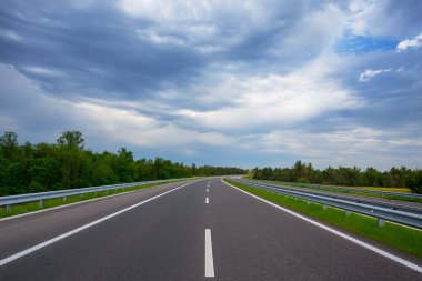 Yoğun bulutlu gökyüzünün altında asfalt yol