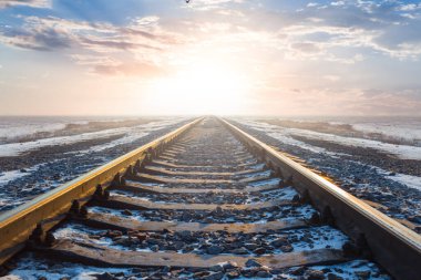 Demiryolu gün batımında uzaklaşıyor, kış ulaşımı arka planda