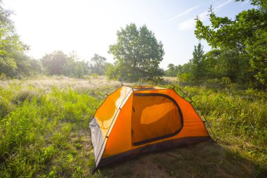 Ormandaki kırmızı turistik çadır. Gün doğumunda, gezi kampı sahnesi., 