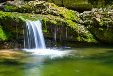 Dağ nehrindeki küçük şelale kanyon boyunca akıyor.