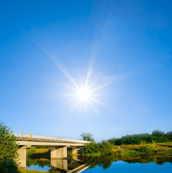 輝く太陽の下で川を渡る小さな橋 — ストック写真