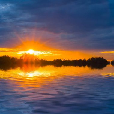 Sessiz göl üzerindeki dramatik günbatımı suya yansıdı