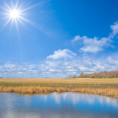 Parlak güneşin altında, çayırların arasında sessiz bir göl