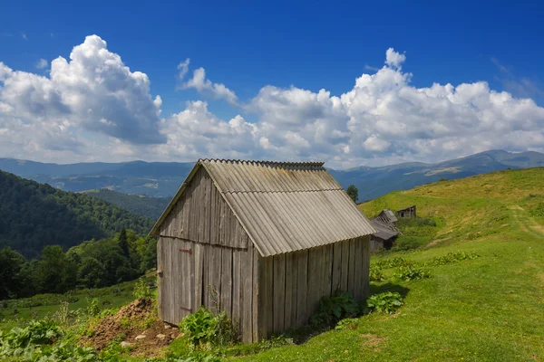 Pequena casa de madeira em colinas verdes — Fotografia de Stock