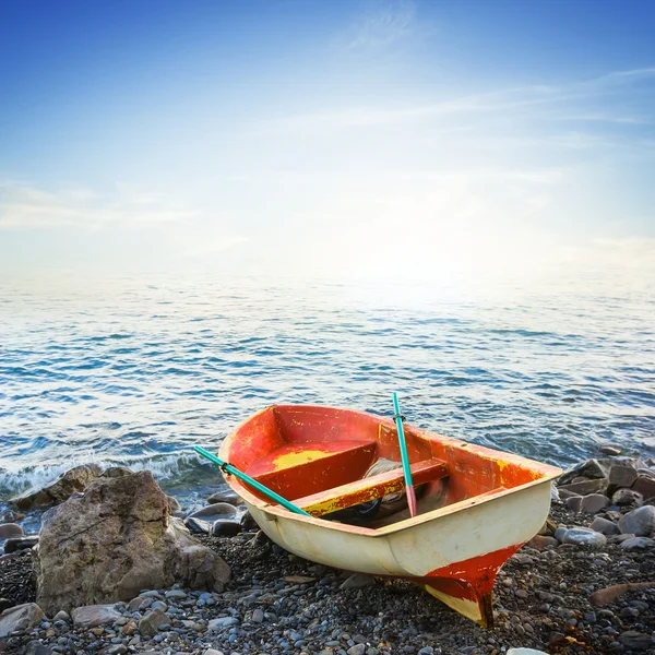 Небольшая лодка на утреннем морском пляже — стоковое фото