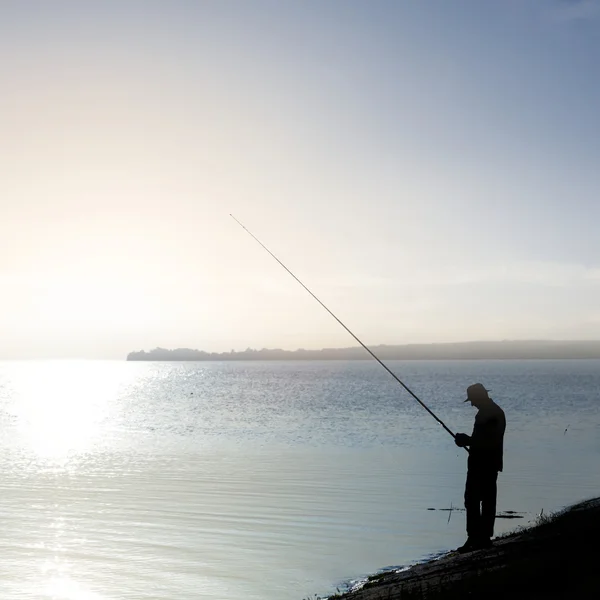 Fisher silhouet aan een rivier — Stockfoto